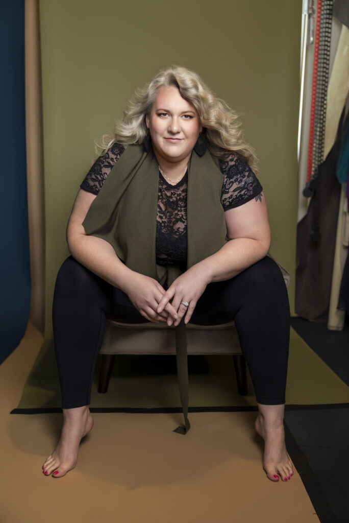 Nicole Howser leaning forward in a chair, elbows on knees, wearing black lace, looking focused and engaged during a Houston personal branding photography session with Bex Wood Luxe Portraits.