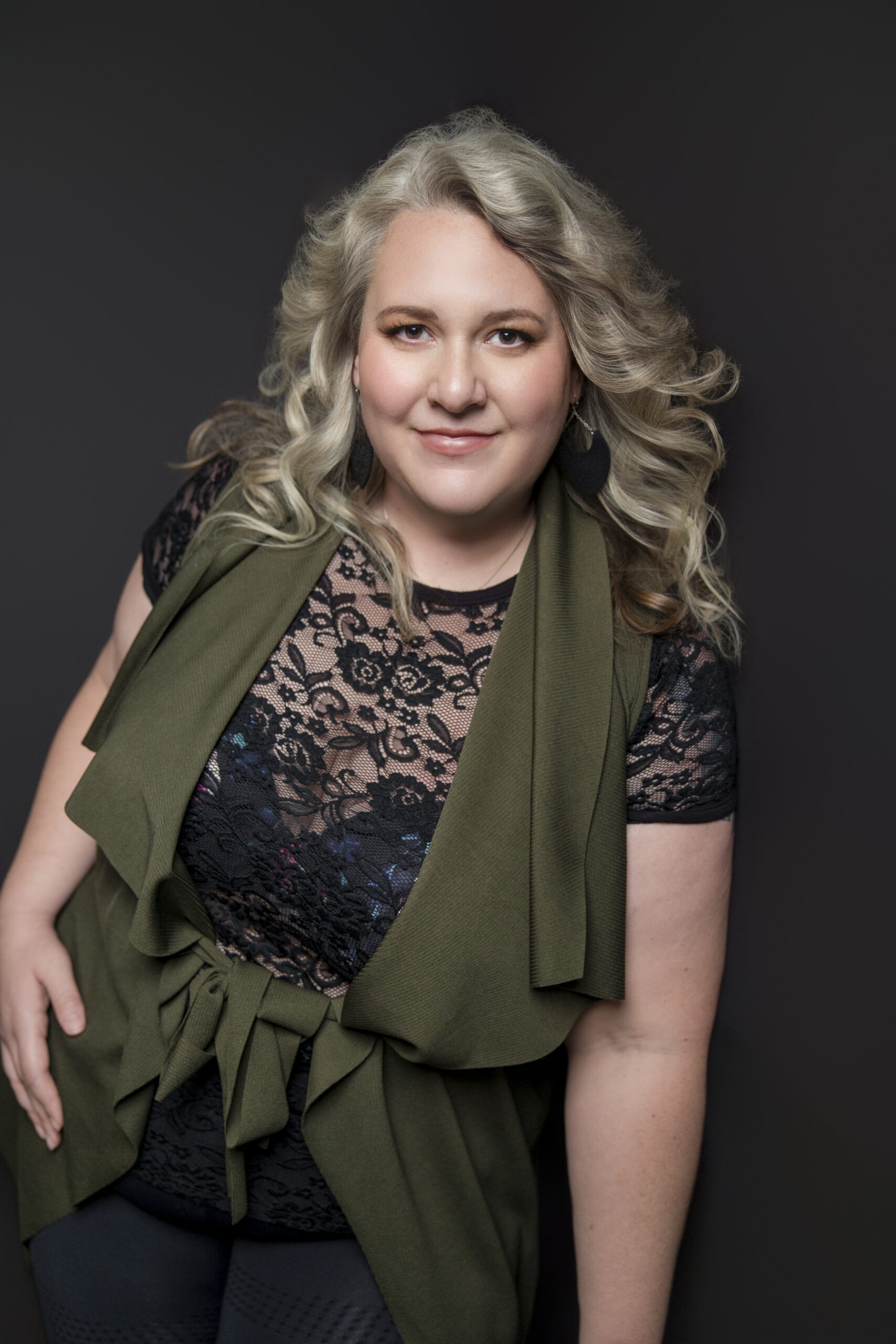 Nicole Howser standing in the studio, silver-blonde curls softly lit, wearing black lace and a green scarf — elegant with an unexpected edge during a Houston personal branding photography session with Bex Wood Luxe Portraits.