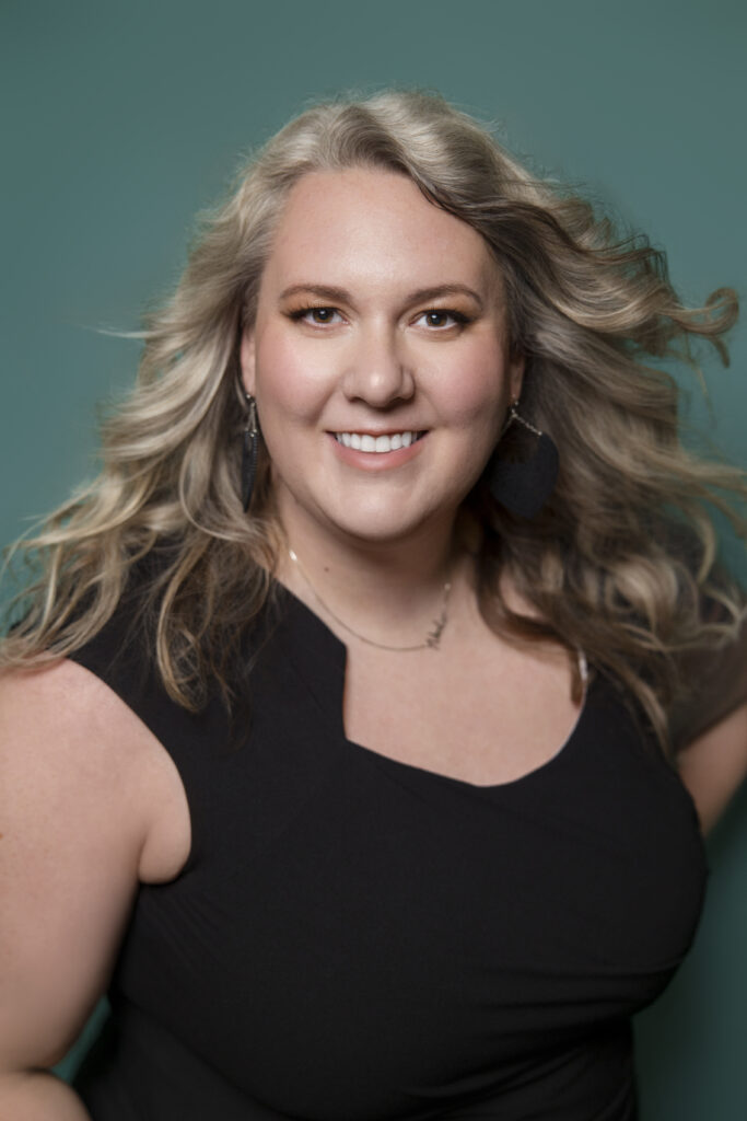 Close-up portrait of Nicole Howser smiling softly, conveying warmth and approachability.